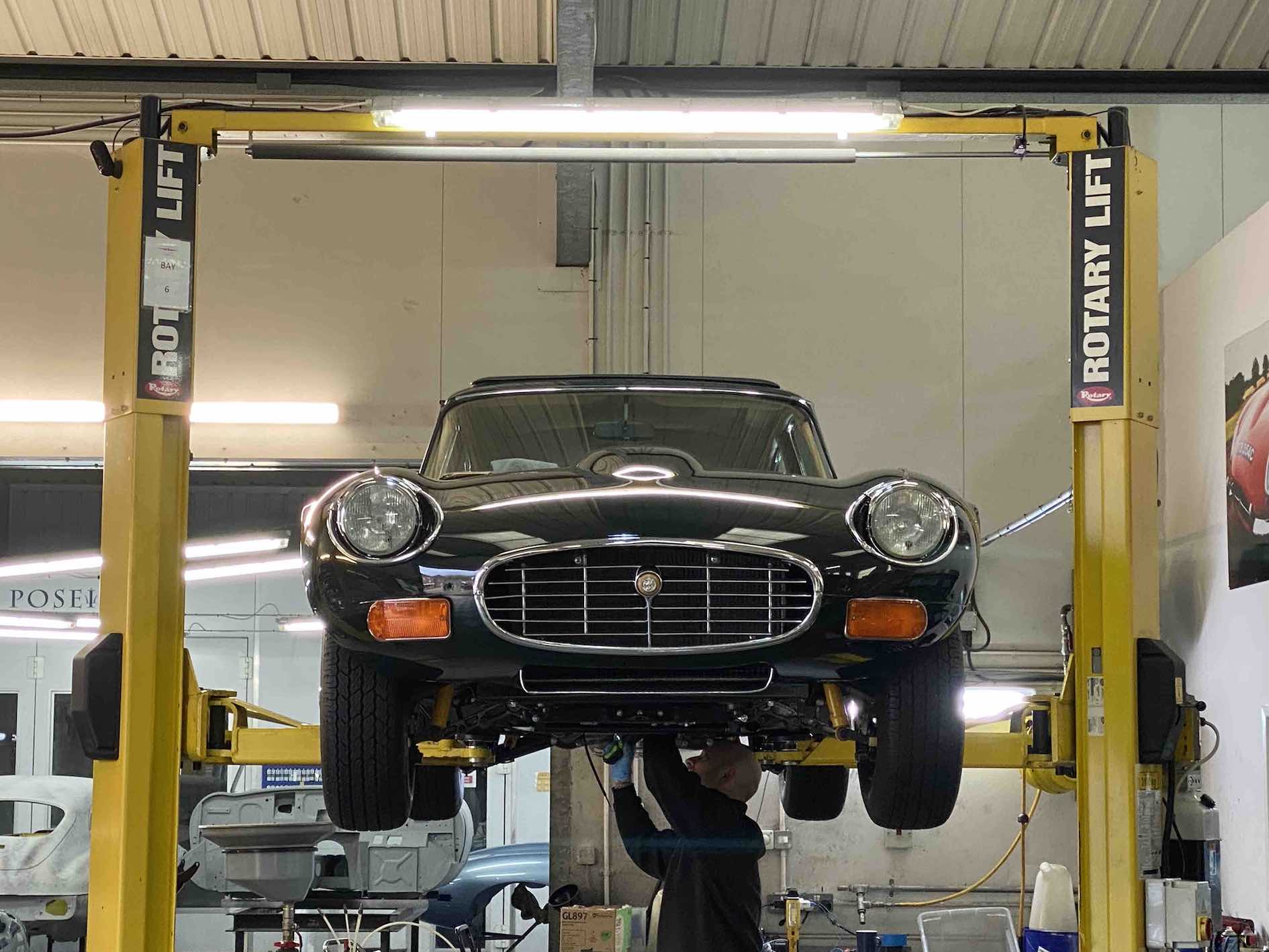 E-type uk Jaguar E-Type on hoist being worked on by mechanic