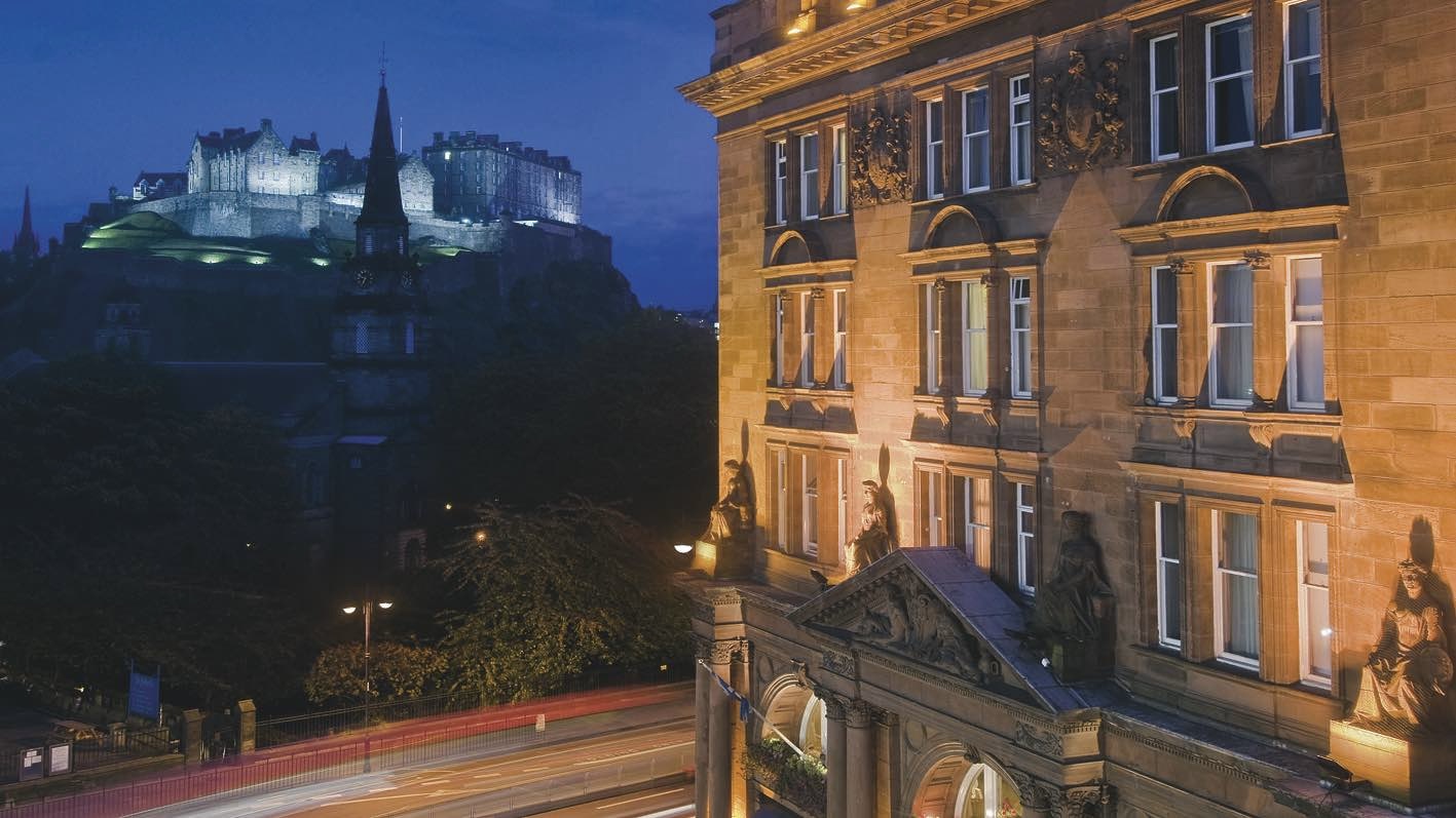 Waldorf Astoria Edinburgh Exterior of one of the best 5-star hotels in Edinburgh, SCotland, at night with castle lit up